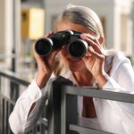 Older woman watching her neighbor with binoculars