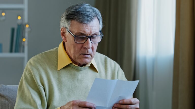 Older man reading a letter and looking upset