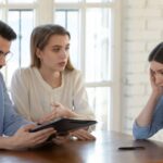 Woman sitting with realtors at a table looking stressed