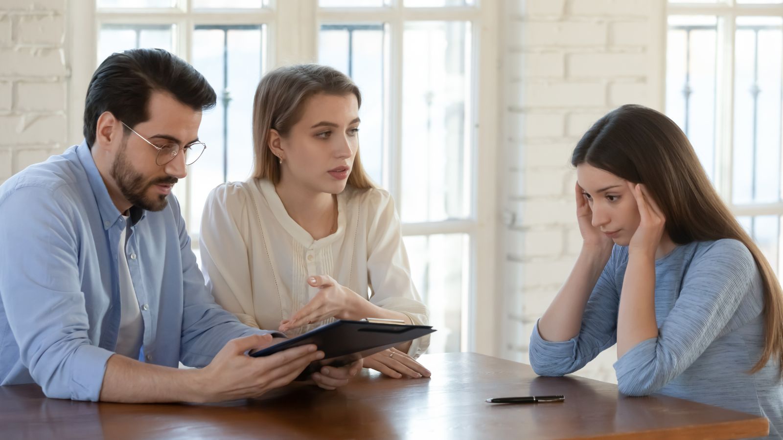Woman sitting with realtors at a table looking stressed