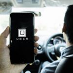 Man holding a phone showing the Uber app on screen