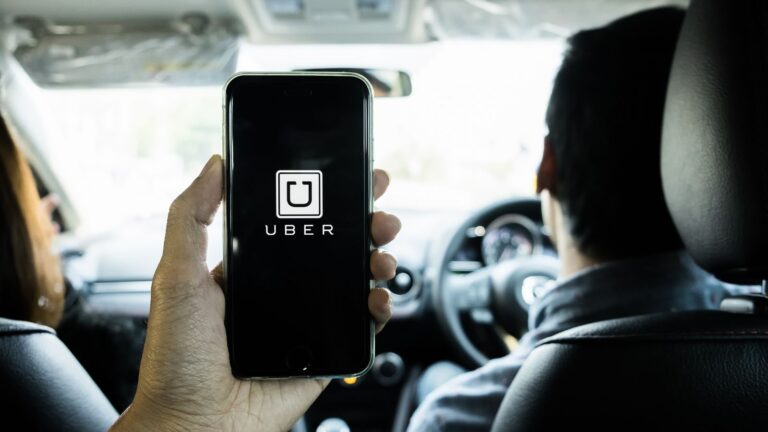 Man holding a phone showing the Uber app on screen