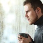 Man drinking coffee and looking out the window