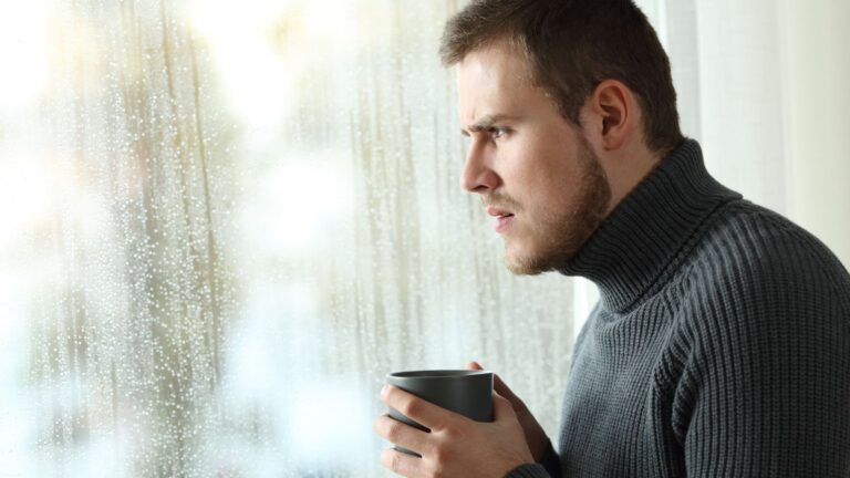 Man drinking coffee and looking out the window