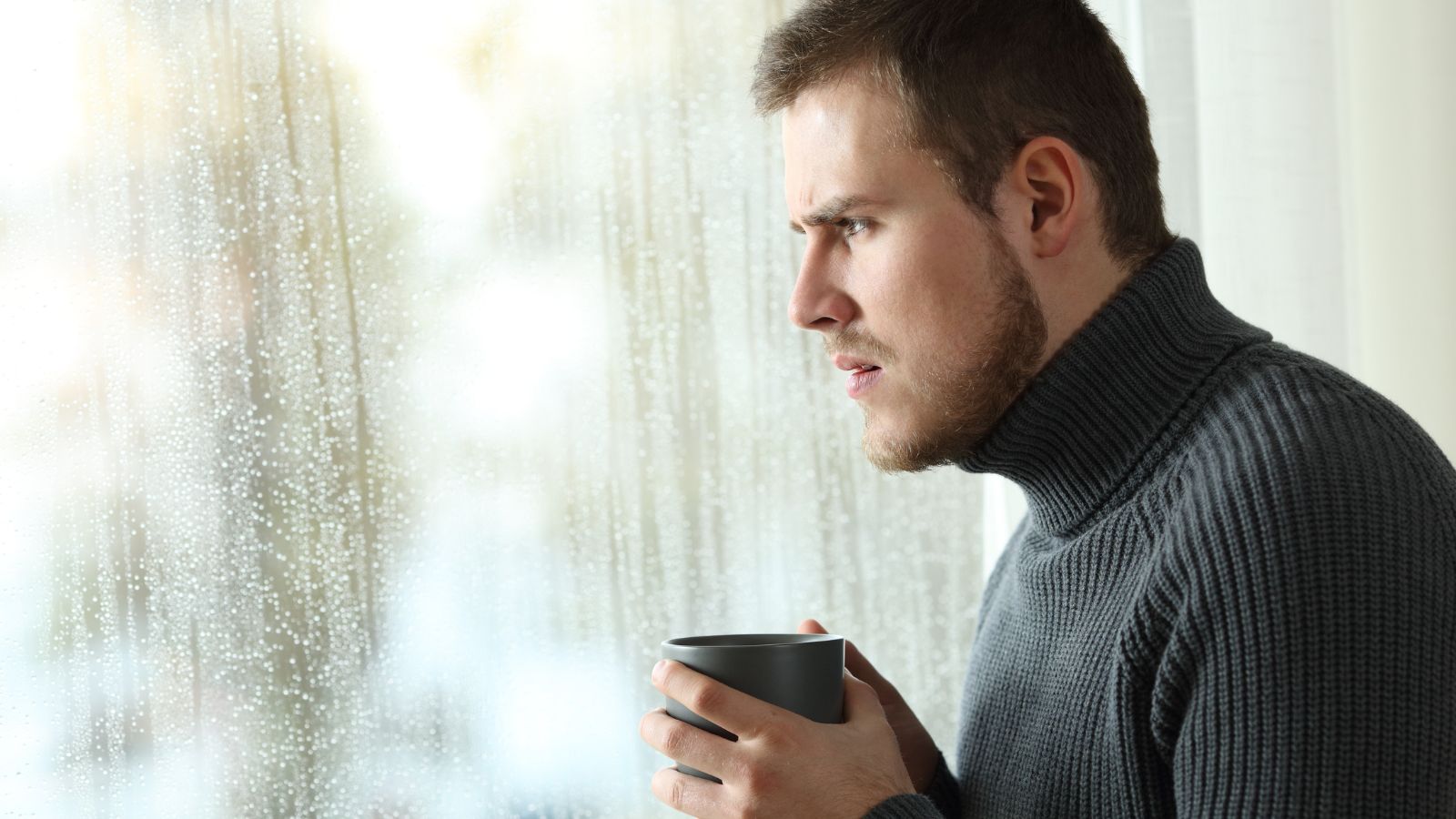 Man drinking coffee and looking out the window