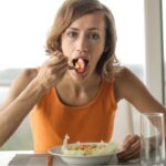 Woman eating lunch by herself looking slightly annoyed