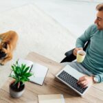 Man working in his home office with his dog laying on the floor