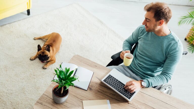 Man working in his home office with his dog laying on the floor