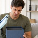 Man opening gift box and looking disappointed