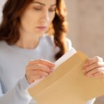 Pensive woman opening a brown letter