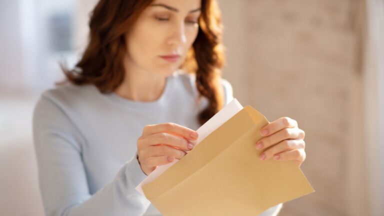 Pensive woman opening a brown letter