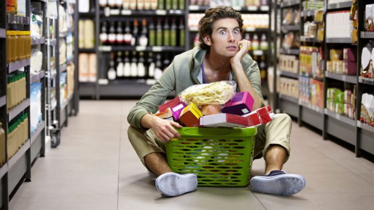 Guy sitting on the floor of the supermarket with a basket full of food