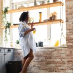 Woman in nightgown looking out kitchen window