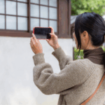 Woman taking a picture of the outside of a house
