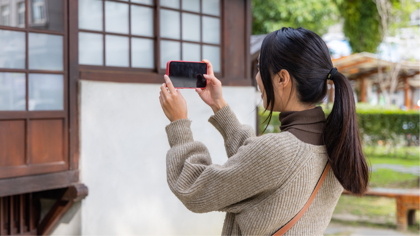 Woman taking a picture of the outside of a house