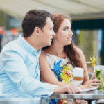 Couple having drinks outdoors at a cafe and looking annoyed
