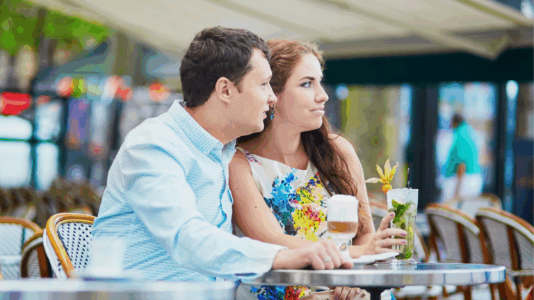 Couple having drinks outdoors at a cafe and looking annoyed