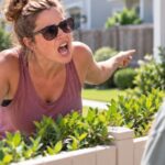 Female yelling at another female over a fence