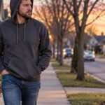 Man in hoodie walking through a neighborhood at dusk